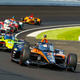 A photo of eight IndyCar racers at a circuit.